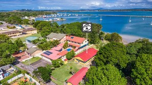 An aerial view of a coastal residential area with houses, a marina, and a clear view of the sea. - Serenity Now Great Location (Iluka)