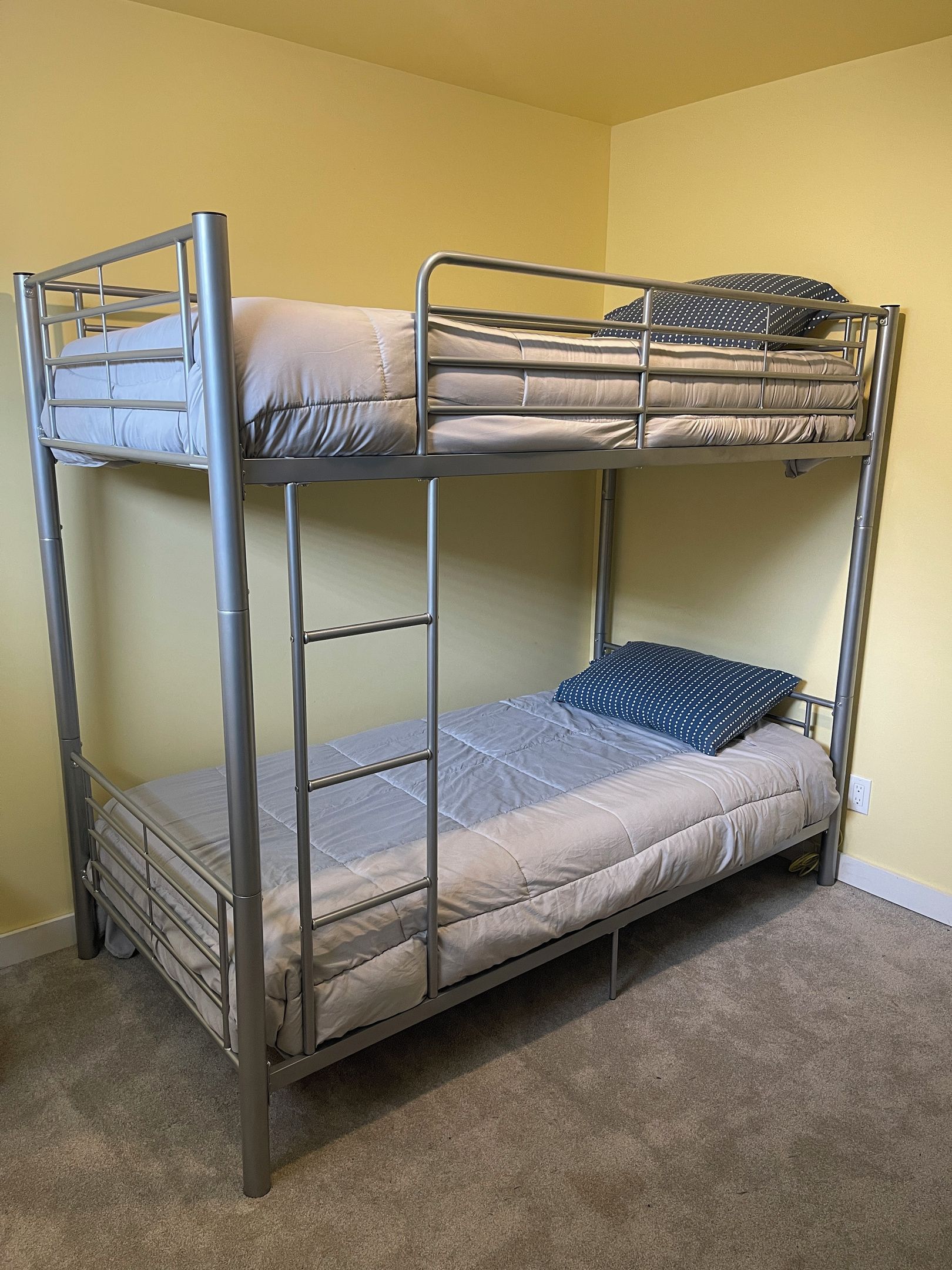 A bunk bed with a metal frame, a mattress, and pillows.