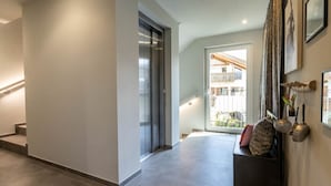 A modern interior with a staircase, a bench with cushions, and a view to an outdoor balcony. - Mali Apartments with balcony and nice views (Tirolo)