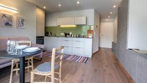 A modern kitchen with white cabinets, a green backsplash, and a dining area with a table set for four. - Mali Apartments with balcony and nice views (Tirolo)