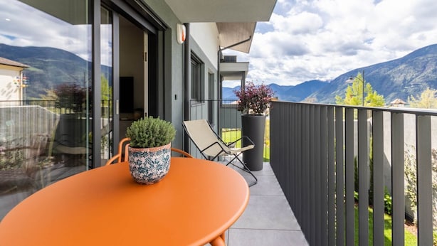 A balcony with a table and chairs, a potted plant, and a view of mountains. - Mali Apartments with balcony and nice views (Tirolo)