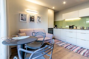 A compact living space with a kitchenette, a dining area with a table and chairs, and a sofa. - Mali Appartments Lounge (Tirolo)