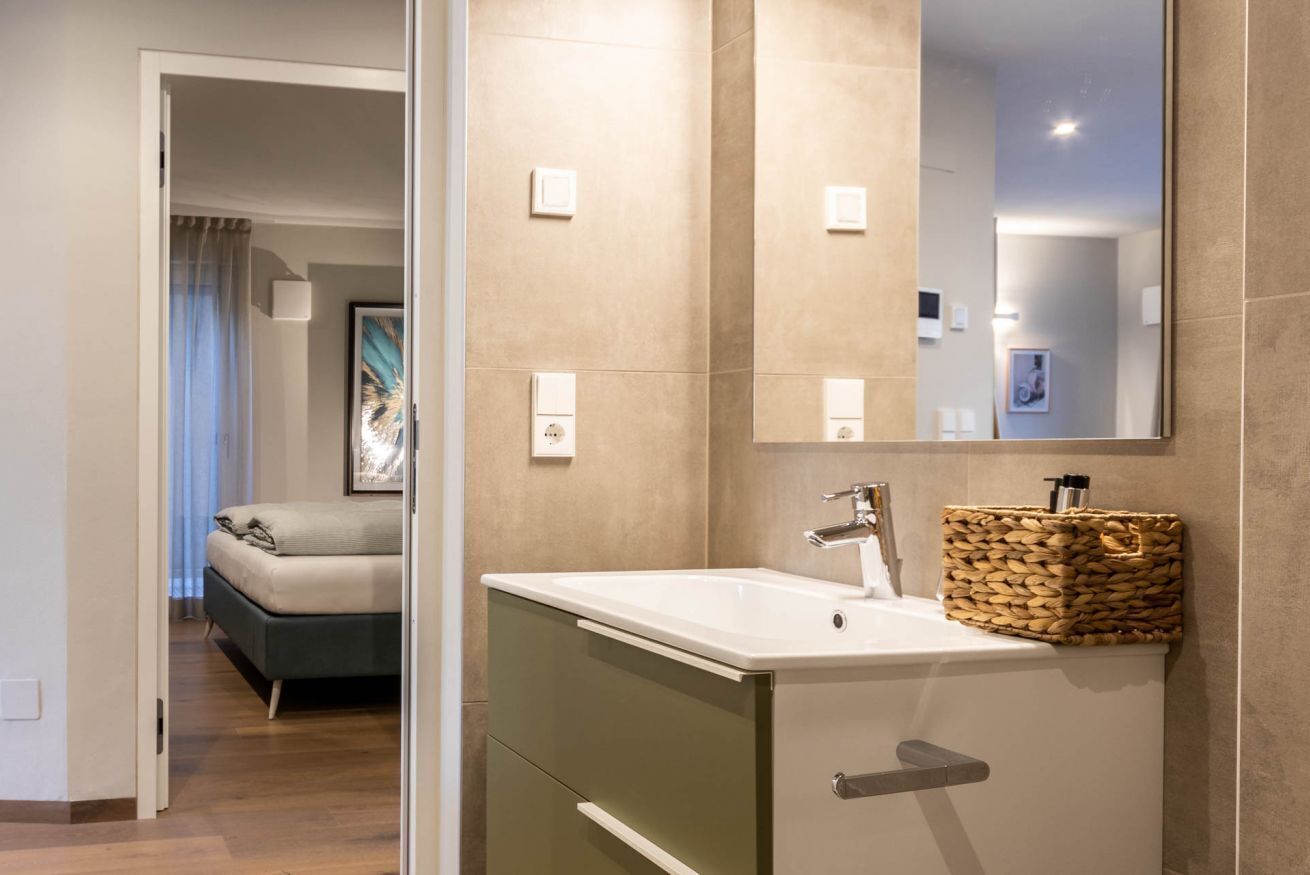 Une salle de bain moderne avec un grand miroir, un lavabo et un meuble de rangement.