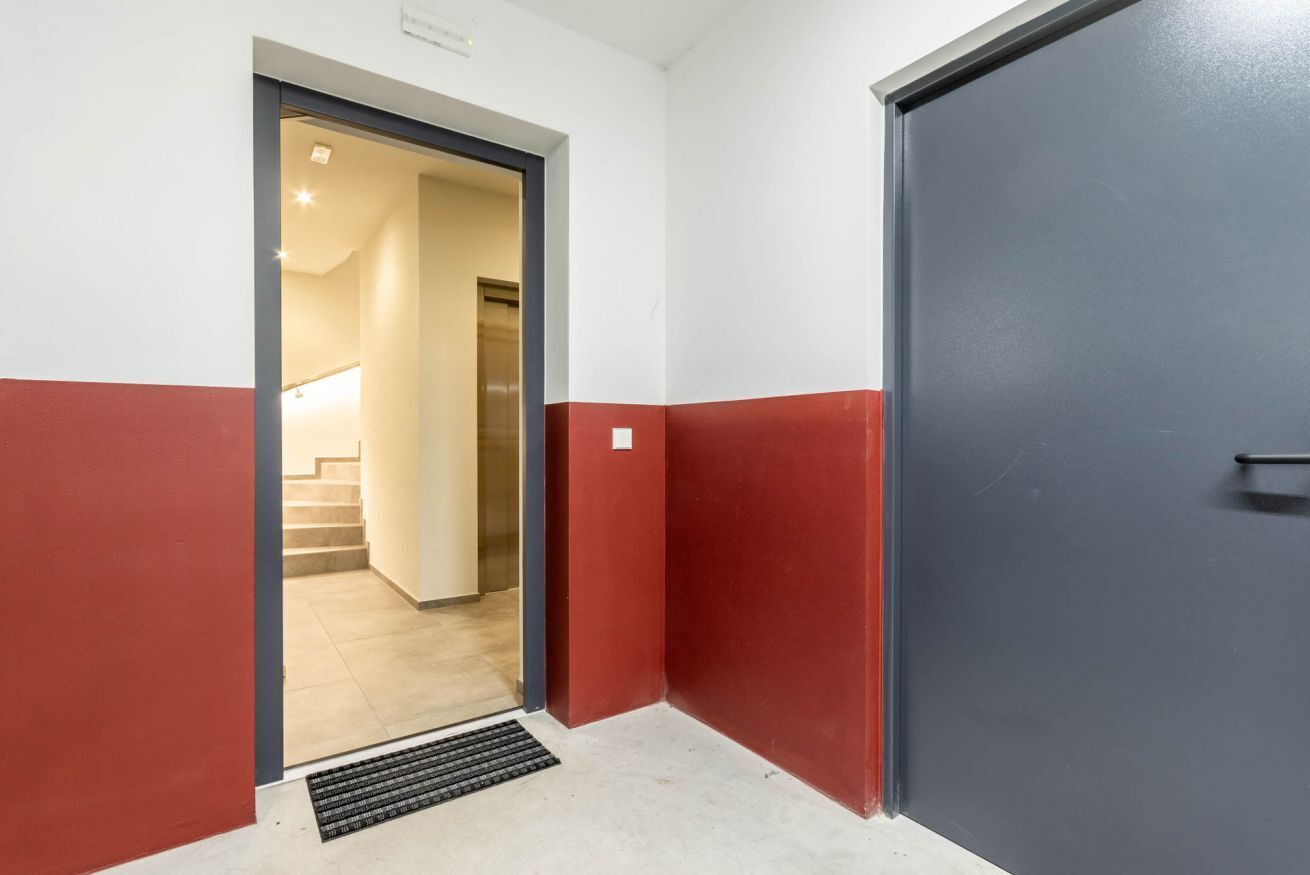Un couloir avec un motif de couleurs rouge et blanc sur les murs, une porte et un escalier menant à une autre pièce.