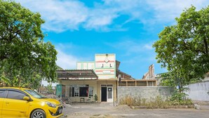 A yellow car parked in front of a building with a visible entrance and a small outdoor seating area. - OYO 91766 Fortuna Hotel Syariah (Paiton)