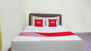 A bed with a white and red bedspread, two red pillows with "OYO" on them, and a brown headboard. - OYO 91766 Fortuna Hotel Syariah (Paiton)