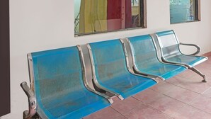 A row of blue metal chairs with metal frames and handles, arranged in a row against a wall with a window. - OYO 91766 Fortuna Hotel Syariah (Paiton)