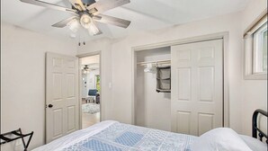 A bedroom with a bed, a ceiling fan, a walk-in closet, and a door leading to another room. - Recently remodeled home with bedrooms and living spaces on the ground floor (Smithville)