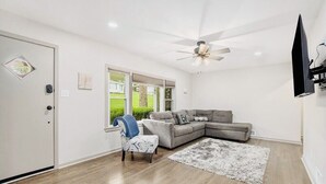 A living room with a grey sectional sofa, a blue armchair, a white rug, and a ceiling fan. - Recently remodeled home with bedrooms and living spaces on the ground floor (Smithville)