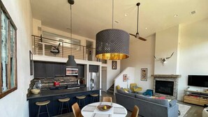 A modern kitchen with a central island, a dining area with a round table and chairs, a living room with a sofa and a fireplace, and a ceiling fan. - Our Happy Place -Downtown Dazzling S Mountain View (Salida)