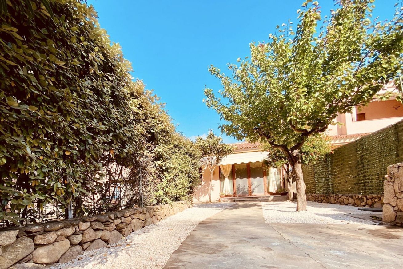 Un patio con un muro de piedra, un camino y un edificio con techo de tejas.