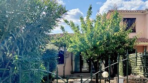 A residential property with a garden, a metal fence, and a building with a tiled roof. - Domo Magenta, Three-room apartment with garden near the center of San Teodoro (San Teodoro)
