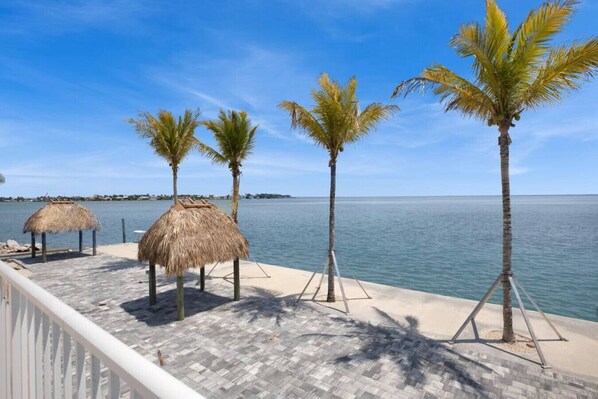 Enjoy a serene beachfront setting with ocean views from shaded seating areas along a paved walkway.