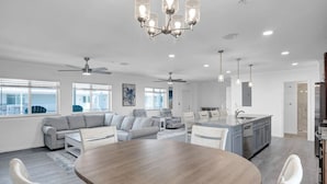 A spacious living room with a large wooden dining table, a gray sofa, and a kitchen area with a granite countertop. - Blue Octopus Hideaway at OI! (Marathon)