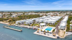 A resort with multiple white buildings, a dock with boats, a swimming pool, and a marina.
