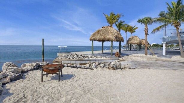 A beach with thatched umbrellas, palm trees, and a sandy walkway. - One bedroom  in United States of America, Marathon (Marathon)