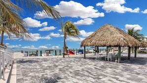 A beachside area with a thatched-roof gazebo, palm trees, and a paved walkway leading to the water. - One bedroom  in United States of America, Marathon (Marathon)