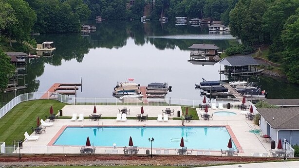 A large rectangular swimming pool surrounded by lounge chairs and umbrellas, with boats docked in the background. - Cozy WATERFRONT condo in a quiet cove.   Private Boat launch (Moneta)