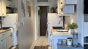 A compact kitchen with white cabinets, a microwave, and a coffee maker. A sign above the door reads "Smith Mountain Lake." - Cozy WATERFRONT condo in a quiet cove.   Private Boat launch (Moneta)