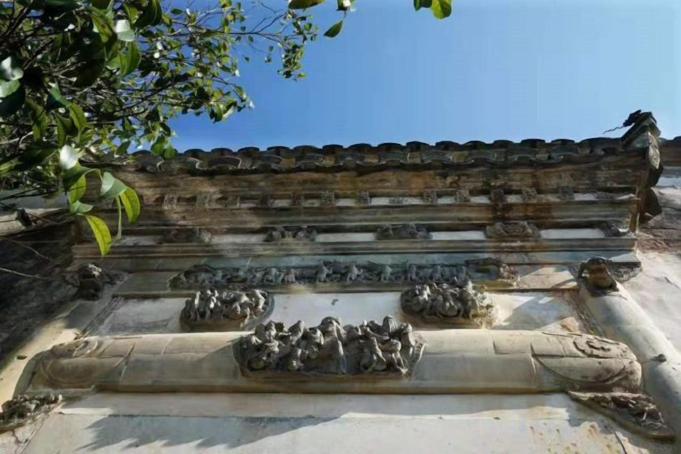 Fachada tradicional de edifício com esculturas em pedra e telhado em cerâmica.