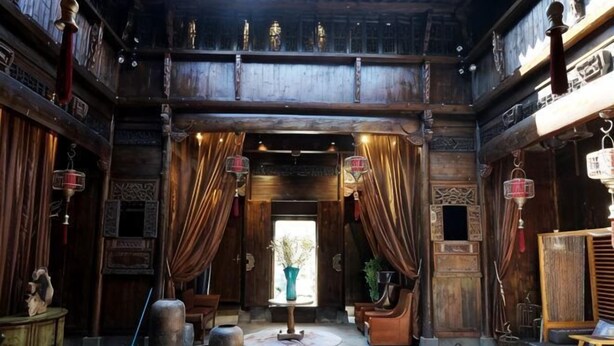 A traditional wooden interior with a central open space, wooden furniture, and hanging lanterns. - Ruiqi Xiangyun Inn (Yi County)