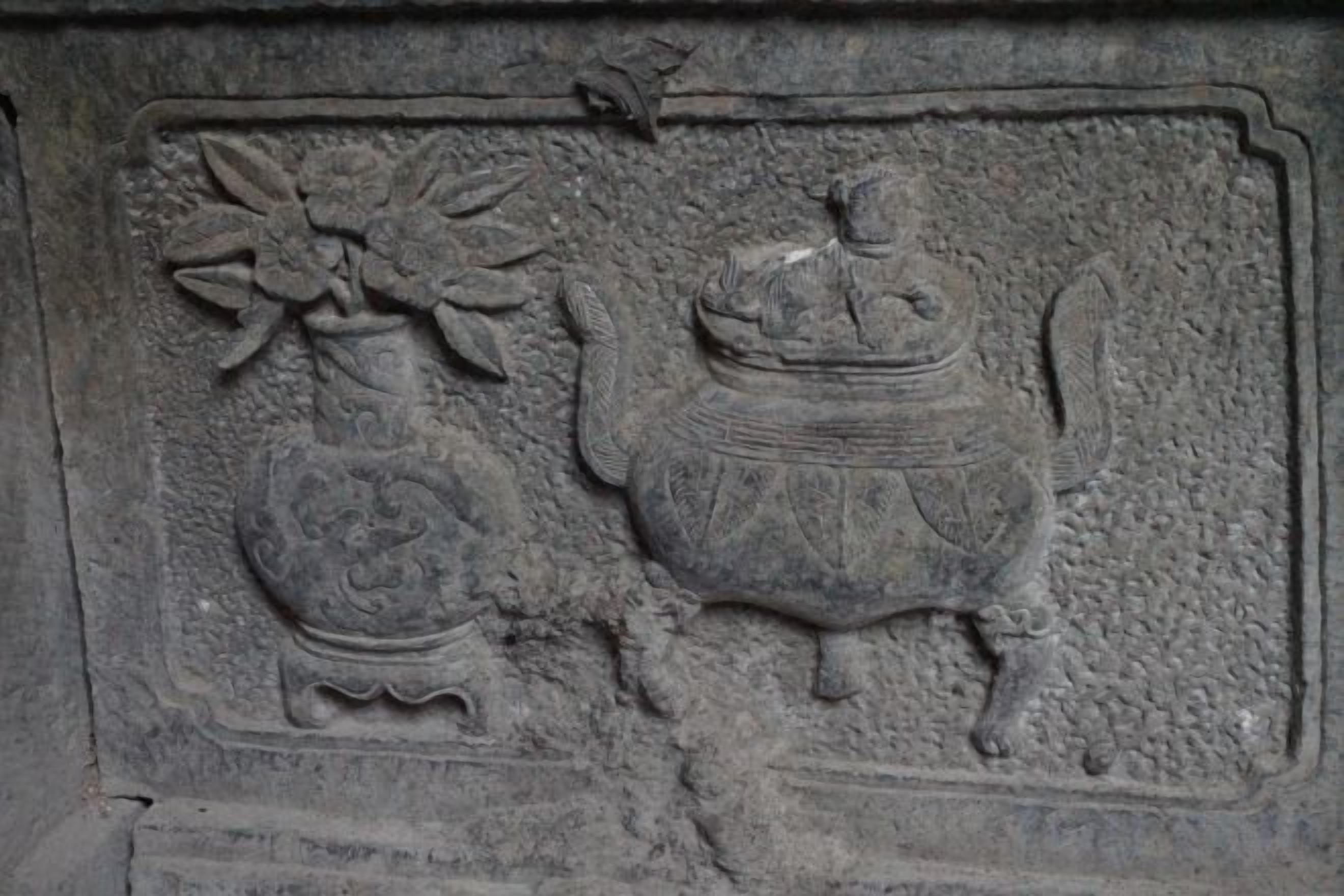 A stone relief with a vase and a pot.