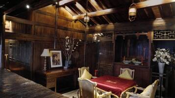 A wooden room with a dining table, chairs, a lamp, and a vase with flowers.