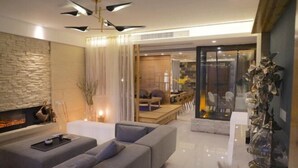 A modern living room with a fireplace, a sofa, a dining area, and a glass partition. - Ruiqi Xiangyun Inn (Yi County)