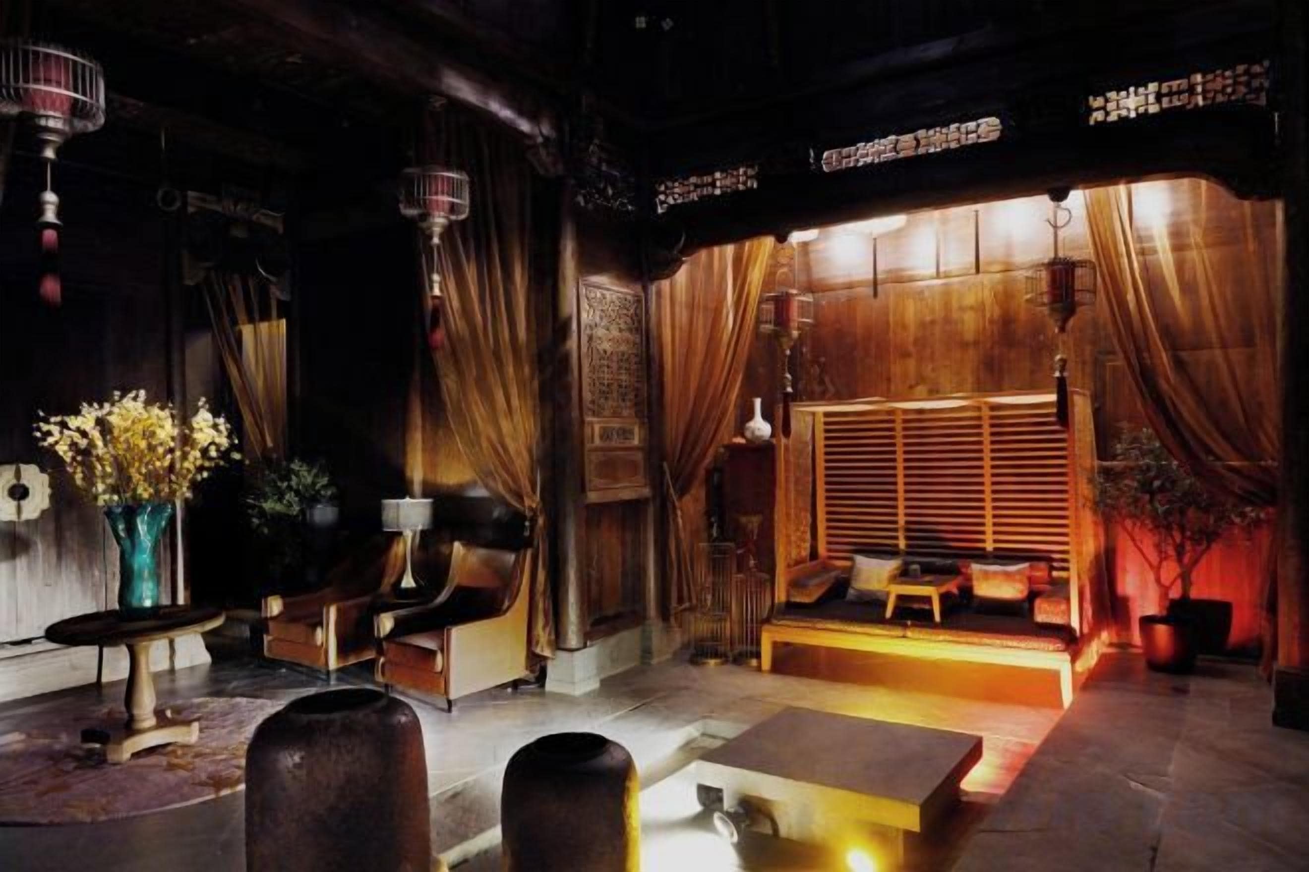 A traditional interior with a wooden floor, a seating area with cushions, and a window with curtains.