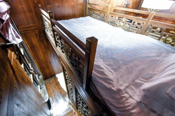 Uma cama de madeira com detalhes entalhados, um guarda-roupa de madeira e uma cabeceira de madeira.