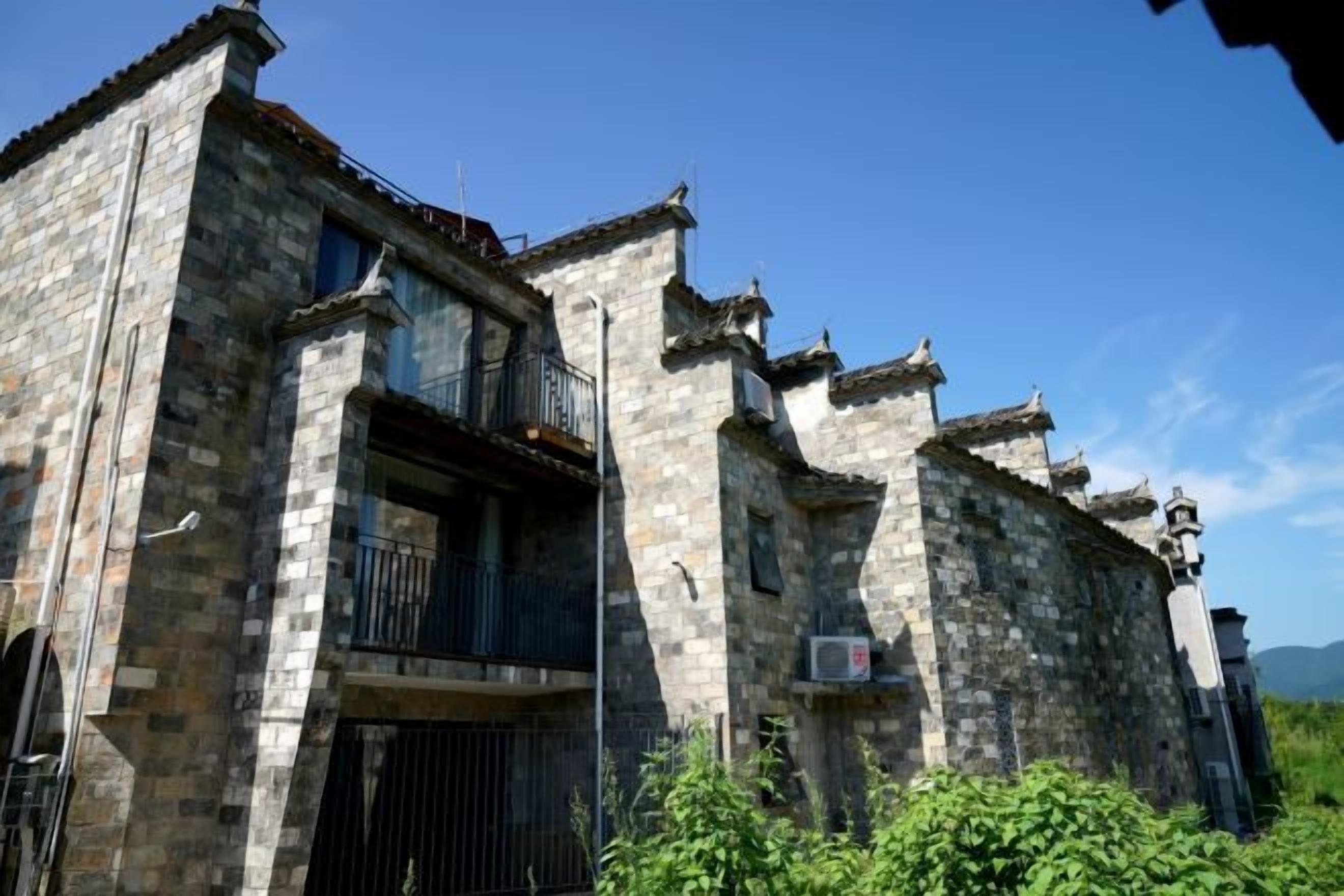 A stone building with a balcony and a gate.
