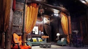 A traditional interior with wooden walls, a sofa, a chair, and a table. - Ruiqi Xiangyun Inn (Yi County)
