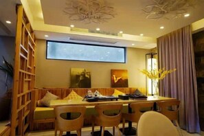 A dining area with a long table, multiple chairs, and a projector screen. - Ruiqi Xiangyun Inn (Yi County)