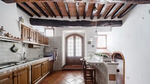 Une cuisine avec des meubles en bois, un pare-feu en carrelage et un sol en pierre.