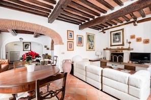 Amplia sala de estar con una mesa de comedor de madera, sofás blancos y una chimenea.