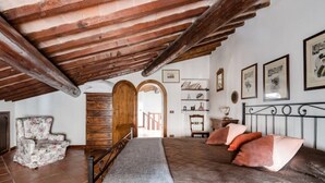 Une chambre à coucher comprenant un lit, une chaise, une armoire en bois et un escalier menant à une autre pièce.