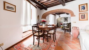 Un coin repas avec une table et des chaises en bois, un tapis à motifs et une cheminée en briques.