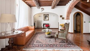 Un salon spacieux avec un canapé en cuir, une table basse ronde et un tapis à motifs.