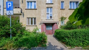 A building with a parking sign, a wheelchair accessibility symbol, and a red door. - Stylish Apartment in Wroclaw | Balcony and Workspace (Wrocław)