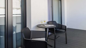 A balcony with two chairs and a small table, a window with blinds, and a door with a curtain. - Stylish Apartment | 500 m to the Beach, Parking, Balcony (Grzybowo)