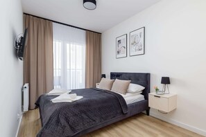 A modern bedroom with a bed, bedside table, and artwork on the wall.