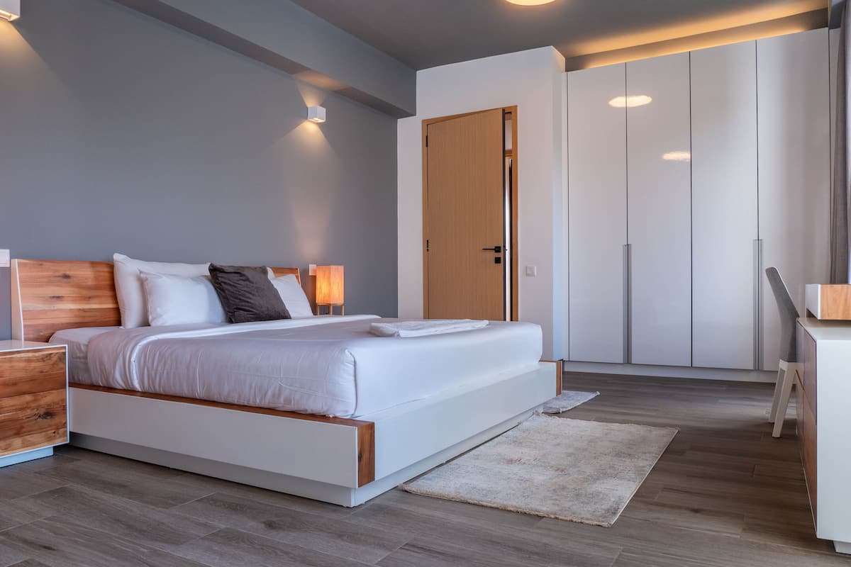 Une chambre moderne avec un grand lit, une tête de lit en bois, des tables de chevet, un bureau et une armoire.