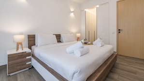A modern hotel room with a large bed, bedside tables with lamps, a wooden wardrobe, and a mirror on the wall. - Purple Haze by Aircasa (Nairobi)