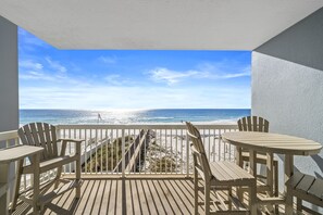A wooden deck with a view of the ocean, a white railing, and two Adirondack chairs. - Pet Friendly-Gulf Front-East Corner Unit-2 Pools (Gulf Shores)