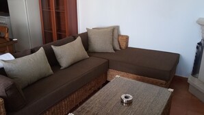 A cozy living area with a brown sectional sofa, two side tables, a fireplace, and a kitchen area with a refrigerator and stove. - El Mirador de Pablo, Casa con Patio Privado (Alomartes)