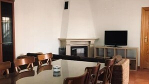 A dining area with a rectangular table and wooden chairs, a television on a stand, and a fireplace. - El Mirador de Pablo, Casa con Patio Privado (Alomartes)