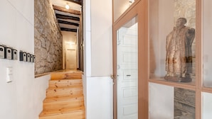 A wooden staircase leading to a room with stone walls, a white door, and a statue. - Artes, the Studio in Porto World Heritage (Porto)