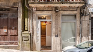A building with a wooden door, a glass door, and a white car parked in front. - Artes, the Studio in Porto World Heritage (Porto)