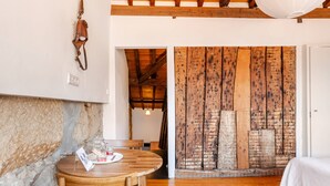 Una habitación con una mesa de madera, una cama y una pared de piedra.