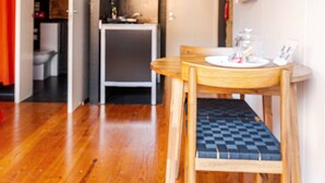 Una cocina moderna con horno empotrado, una pequeña encimera y una mesa de comedor de madera con una silla.